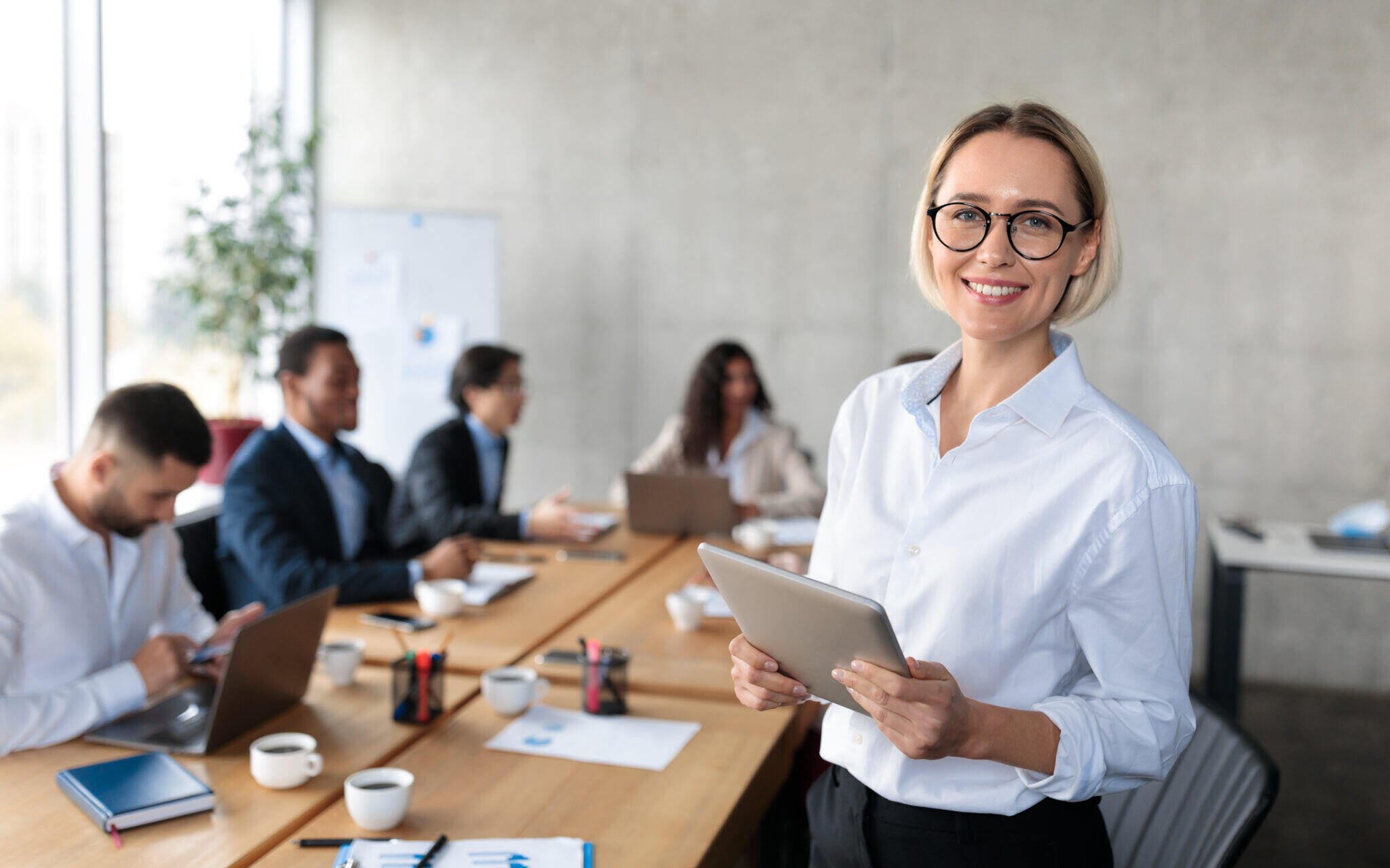 successful-businesswoman-holding-digital-tablet-standing-in-modern-office-stockpack-adobe-stock-2048x1280